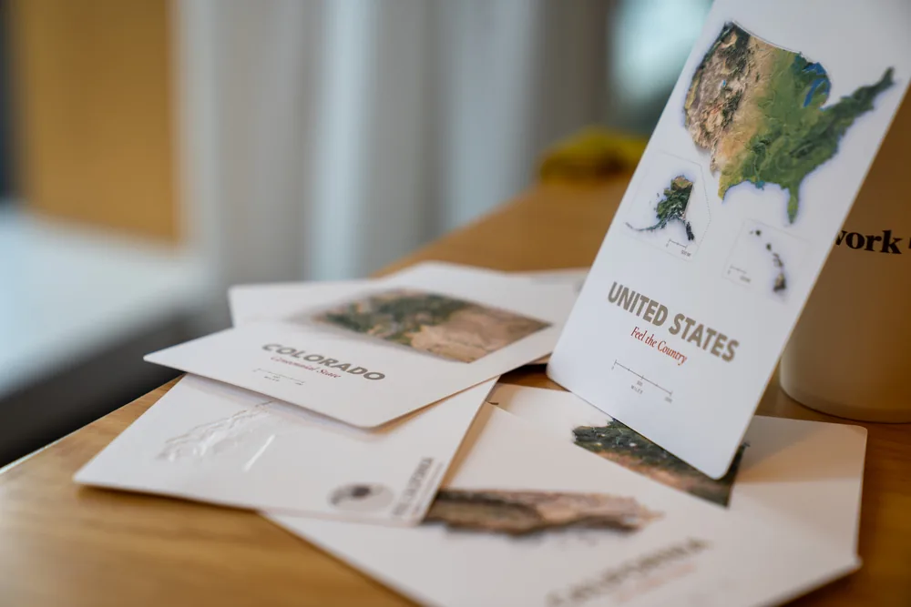 Far Maps production proofs arranged across a warm wooden tabletop