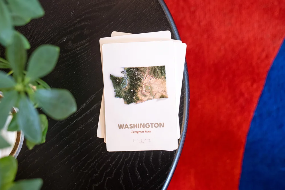 Washington raised-relief postcard production proof resting on a neat stack of proof cards