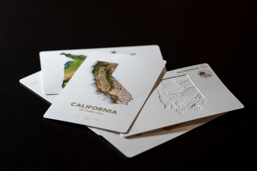 Far Maps production proofs stacked to show raised fronts, printed backs, and card edges